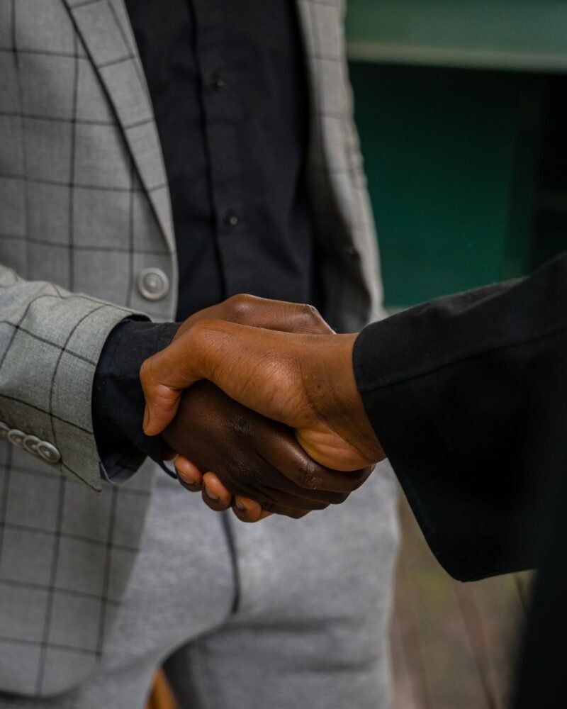 Two people in business attire shaking hands to close a deal.