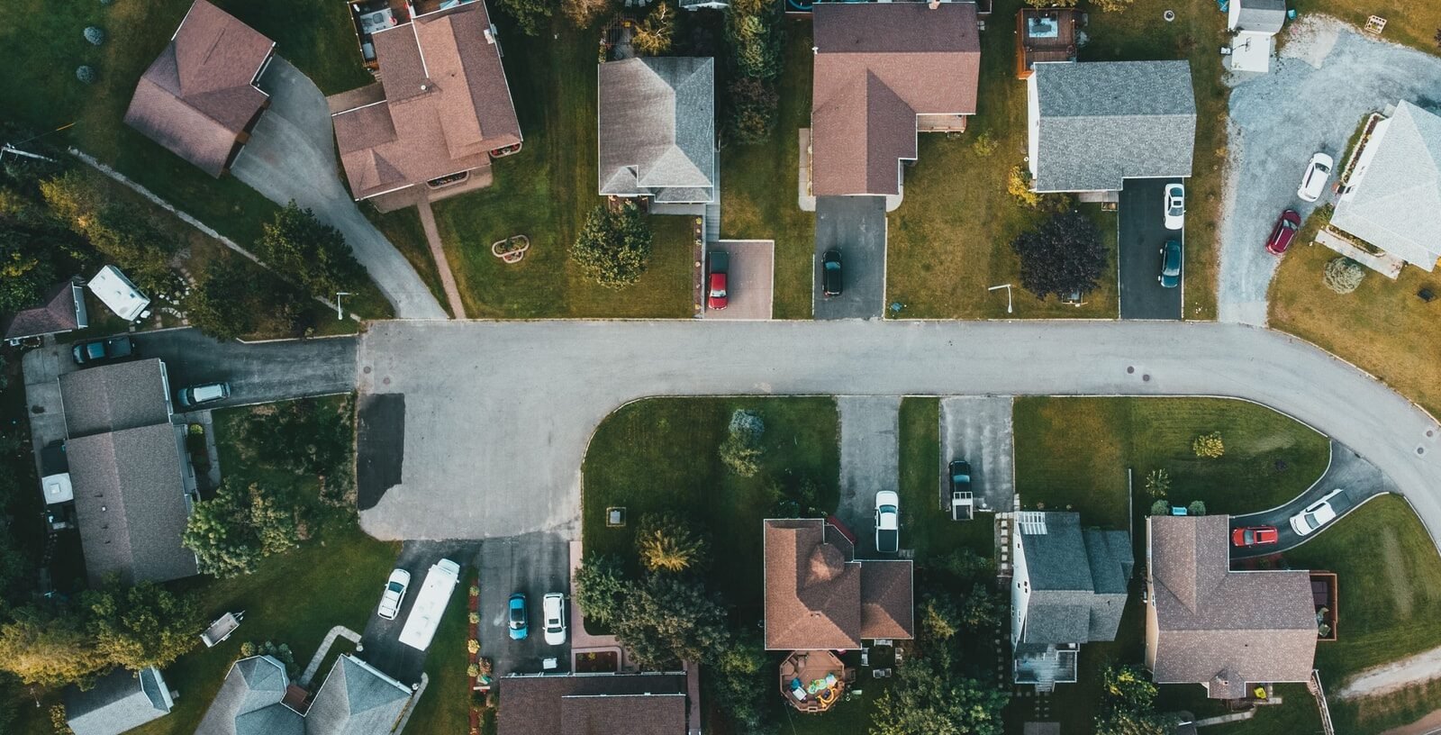 Aerial view of a curving suburban street lined with houses and trees