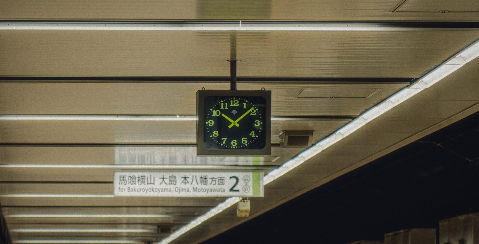 A station clock hanging above a subway platform