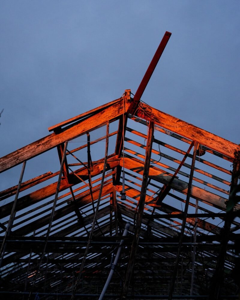 The exposed steel roof frame of a building under construction against a dusk sky